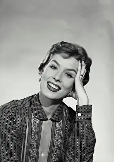 Hand In Hair Prints: Vintage Photograph. Smiling woman with short hair wearing blouse with floral designs and stripes resting head on hand