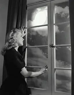 Blonde Prints: Vintage Photograph. Blonde woman looking longingly out window at night sky with large bright moon