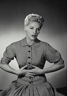 Vintage Photograph. Blonde woman with short hair holding hands to stomach in discomfort