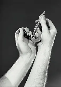 Measurement Prints: Vintage photograph. Close up view of hands holding micrometer caliper