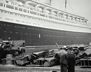 New York State Prints: Vintage photograph. Couple in front of steel beams on dock with Queen Elizabeth ship in background