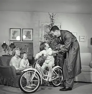 Bicycle Prints: Vintage Photograph. Family gathered around Christmas tree father and child play with bicycle
