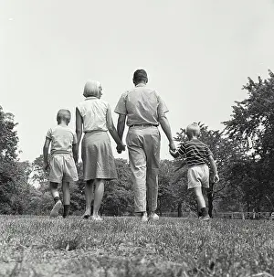 Parenting Prints: Vintage Photograph. A family group walking holding hands away from camera