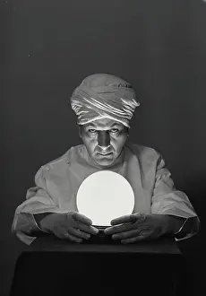 One Mid Adult Man Only Prints: Vintage Photograph. Fortune teller with glowing crystal ball on table