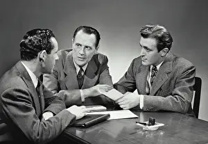 Businessmen Prints: Vintage photograph. Group of businessmen sitting at desk having meeting