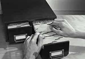 Organizing Prints: Vintage photograph. High angle view of a businessman filing cards in drawer