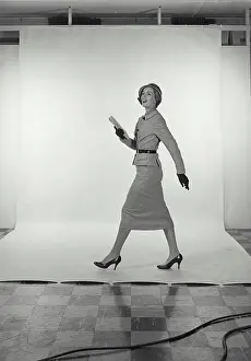 Skirt Prints: Vintage Photograph. Full length view of woman wearing light grey skirt and jacket and hat on white studio background