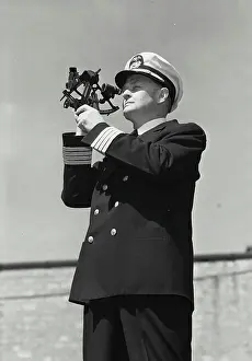 50 55 Years Prints: Vintage Photograph. Man in captains uniform standing and looking through sailor protractor off into the distance
