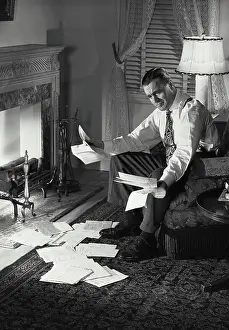 Mail Prints: Vintage photograph. Man by fireplace sorting mail