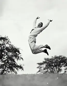 : Vintage photograph. Man jumping in the air while pushing arms and legs back