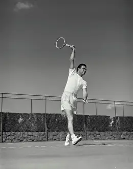 Serve Prints: Vintage Photograph. Man returns hit to other side in tennis match he has his racket up high above his head