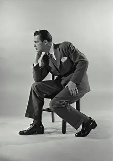 Business Suit Prints: Vintage Photograph. Man in suit sittin gon chair with chin rested on fist