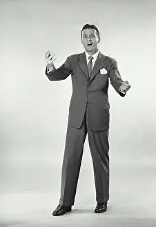 Raised Prints: Vintage photograph. Man in suit standing with arms raised