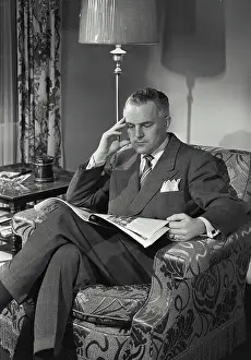 Meme Prints: Vintage photograph. Man in suit and tie sitting and reading paper
