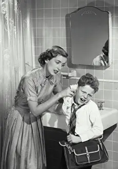 Cleaning Prints: Vintage photograph. Mother cleaning unhappy young boys ear