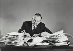 Stack Prints: Vintage photograph. Older man in pinstripe suit sitting at desk full of papers