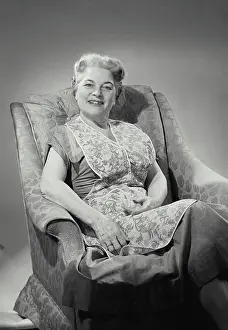 Older Woman Prints: Vintage Photograph. Older woman in apron sitting in chair. Frame 3