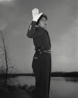 Gloves Prints: Vintage photograph. Policeman blowing whistle while holding up hand