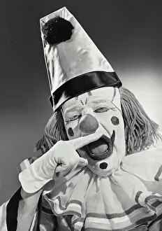 Finger Prints: Vintage photograph. Portrait of clown wearing silly hat biting finger