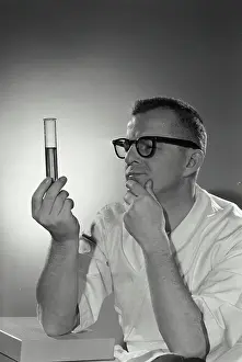 Analysis Prints: Vintage Photograph. A portrait of a scientist looking at a test tube quizzically