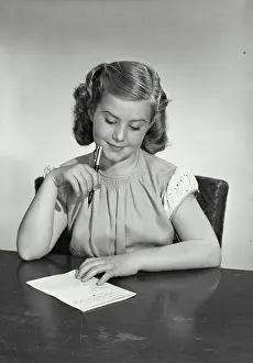Dreaming Prints: Vintage photograph. Portrait of young girl sitting at table writing letter and thinking