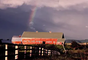 Pasture Prints: Vintage Photograph. A rainbow arches over a rustic red barn against a dramatic cloudy sky