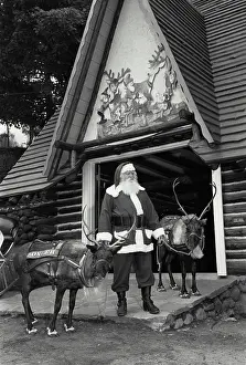 Deer Prints: Vintage Photograph. Santa Claus standing with two reindeer in front of a building