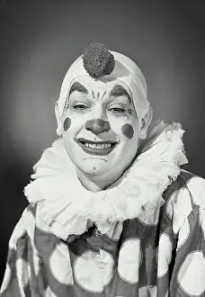 Circus Prints: Vintage Photograph. Smiling man in clown costume and makeup with fuzzy ball on head and eyes squinting
