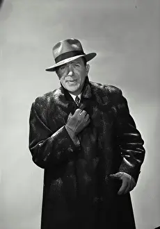 Business Suit Prints: Vintage Photograph. Smiling man wearing hat and winter coat dusted with snow holding collar together looking cold