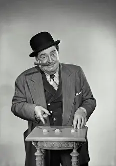 Smoking Prints: Vintage Photograph. Street gambler with cigar in mouth pointing at shells of nuts for game