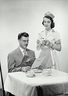 Dinner Prints: Vintage photograph. Studio scene of waitress taking order from man sitting at table looking at menu