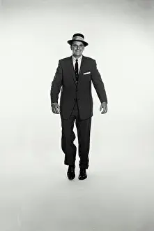 Traditional Attire Prints: Vintage Photograph. A studio shot of a man in a dark suit walking towards the camera