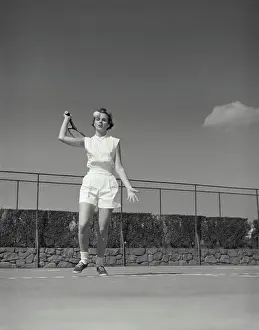 Serve Prints: Vintage Photograph. Woman gets ready to hit tennis ball on court she is in the serving position