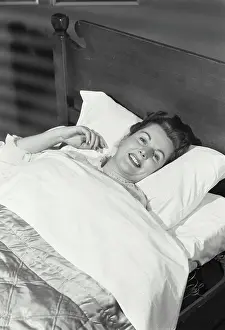 Vintage Photograph. Woman lying in bed smiling