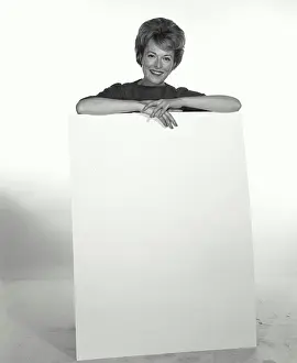 Elegance Prints: Vintage Photograph. A woman standing behind a white board holding it with her hands smiling