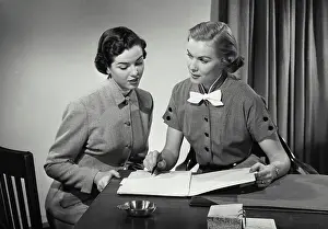 Businesswomen Prints: Vintage Photograph. Two women in business office sitting at desk having conversation