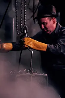 Industry Prints: Vintage Photograph. Worker in protective gear operating industrial machinery amidst steam and smoke