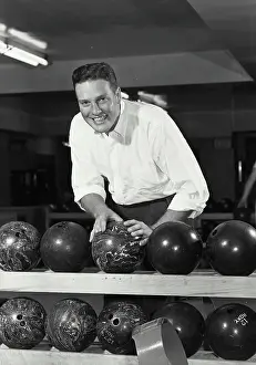 Ball Prints: Vintage photograph. Young adult man grabbing bowling ball off of rack