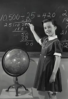 Mathematics Prints: Vintage photograph. Young girl in dress writing on chalkboard