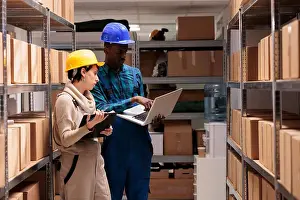Maintenance Prints: Warehouse supervisors discussing goods inventory, checking report on laptop