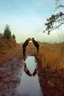Lgbt Prints: Water slop with reflection of homosexual couple embracing and kissing on road