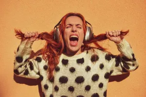 Hear Prints: White Caucasian woman with red hair wearing helmets to protect herself from noise pulls her pigtails while screaming