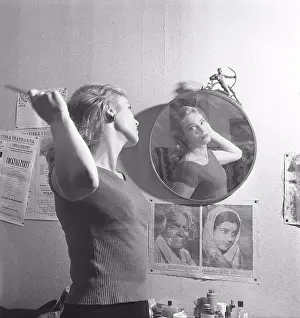 Refle Ction Prints: Woman in the 1950s. A young woman is standing in front of a mirror combing her hair
