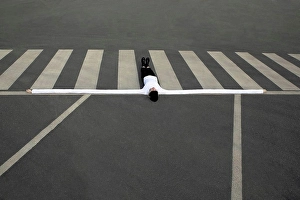 Curve Prints: Woman with artificial long hands lying on zebra crossing