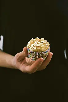 Breakfast Prints: A woman with black dress holding a carrot muffin photographed from front view