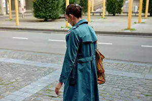 Chic Prints: Woman in a blue trench coat walking on a city sidewalk with a yellow shoulder bag