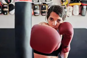 Mixed Prints: Woman in boxing gloves trains while looking at the camera