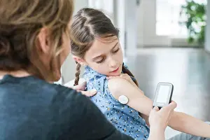 Electronics Prints: Woman checking blood sugar level (self glycemia) of a diabetic child with FreeStyle Libre ®