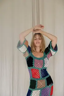 Individuality Prints: woman in colorful crochet dress dancing by beige curtains