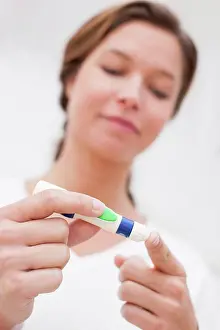 Diabetes Prints: Woman doing finger prick test for blood glucose